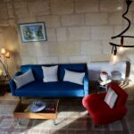 Salon du gîte Camargue avec canapé, fauteuil et table basse, mur en pierre, Mas de l'Hermitage à Arles